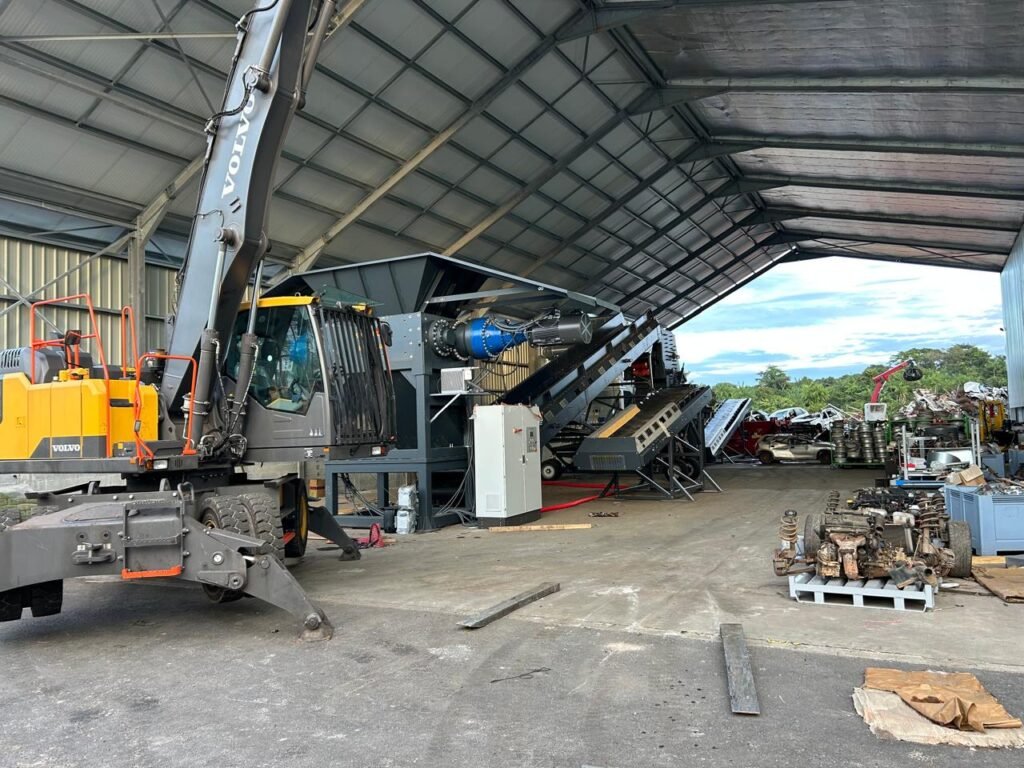 Chantier industriel avec machines et grues sous hangar.
