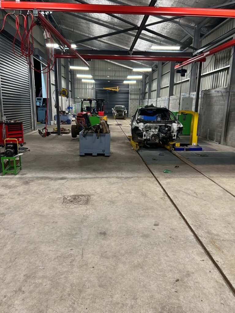 Atelier avec voitures en réparation et outils divers.